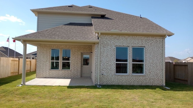 rear view of property with a yard, roof with shingles, a patio, and a fenced backyard