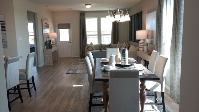 dining room featuring a chandelier, baseboards, and wood finished floors