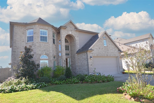 view of front facade featuring an attached garage, driveway, brick siding, and a front yard