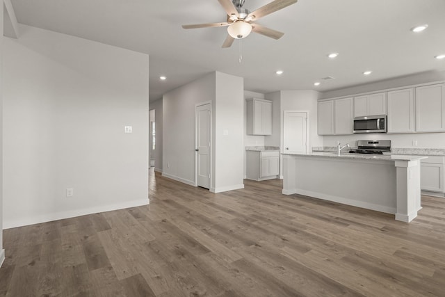 kitchen with a ceiling fan, baseboards, light wood finished floors, recessed lighting, and appliances with stainless steel finishes