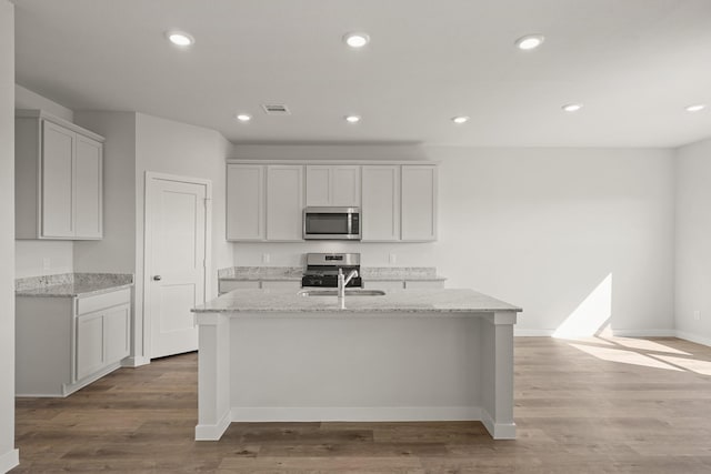 kitchen featuring visible vents, a center island with sink, wood finished floors, recessed lighting, and appliances with stainless steel finishes