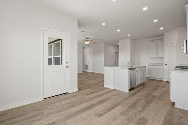 kitchen featuring a ceiling fan, a sink, open floor plan, stainless steel appliances, and light wood finished floors