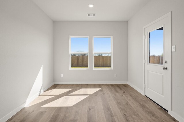 spare room featuring a wealth of natural light, visible vents, baseboards, and wood finished floors