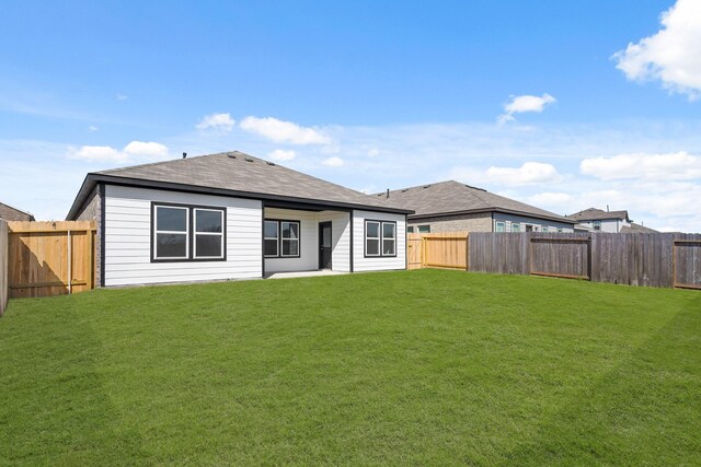 rear view of property with a yard and a fenced backyard