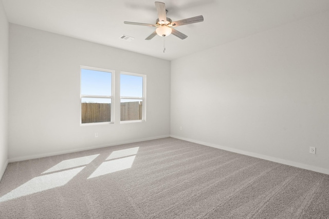 carpeted spare room with baseboards, visible vents, and ceiling fan