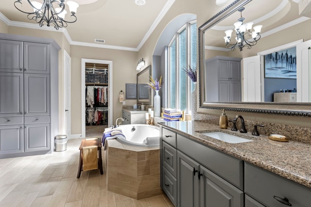 full bath featuring a chandelier, a garden tub, visible vents, a spacious closet, and ornamental molding