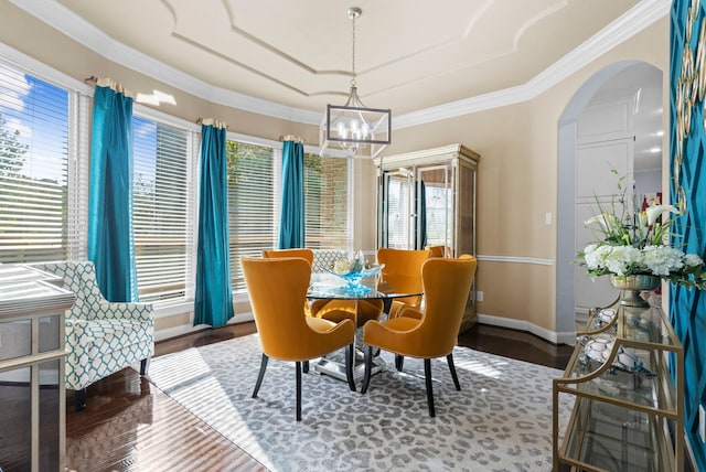 dining room with arched walkways, a notable chandelier, wood finished floors, baseboards, and crown molding