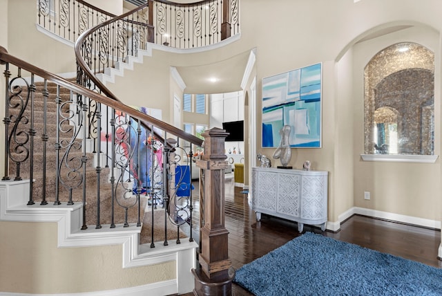 foyer entrance with dark wood finished floors, a towering ceiling, and baseboards