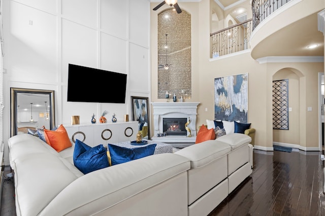 living room featuring a towering ceiling, dark wood-style floors, and a ceiling fan