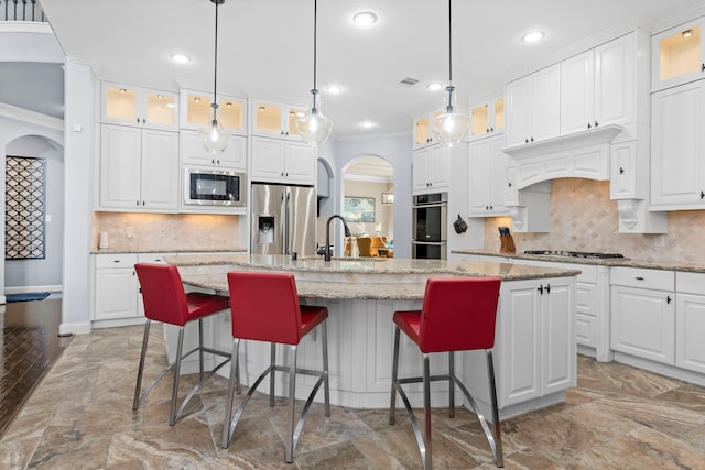 kitchen with glass insert cabinets, a center island with sink, and appliances with stainless steel finishes