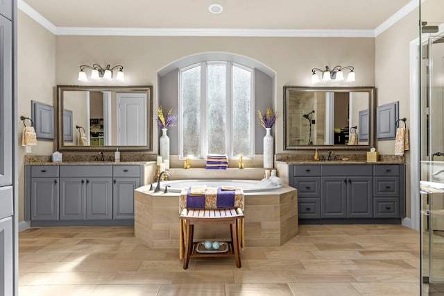 full bath with crown molding, two vanities, a garden tub, and a sink