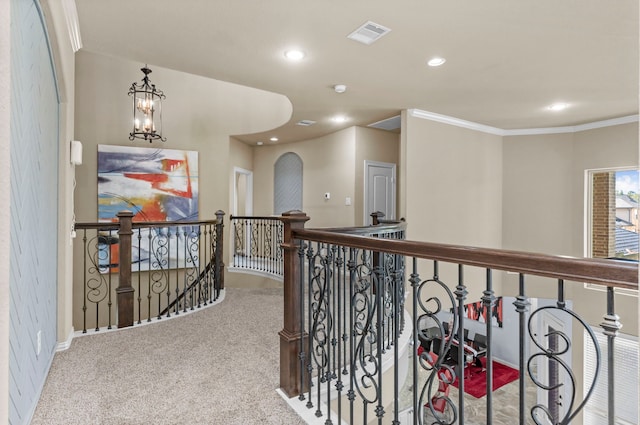 corridor featuring visible vents, ornamental molding, carpet flooring, an upstairs landing, and a chandelier