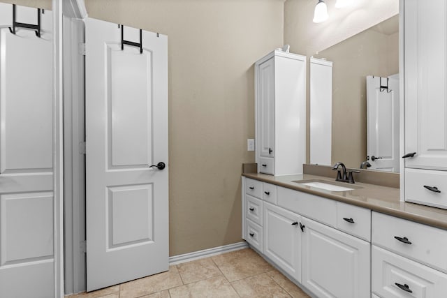 bathroom featuring a textured wall, vanity, baseboards, and tile patterned floors