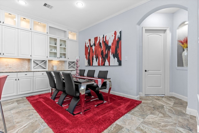 dining area featuring arched walkways, visible vents, baseboards, stone finish flooring, and crown molding