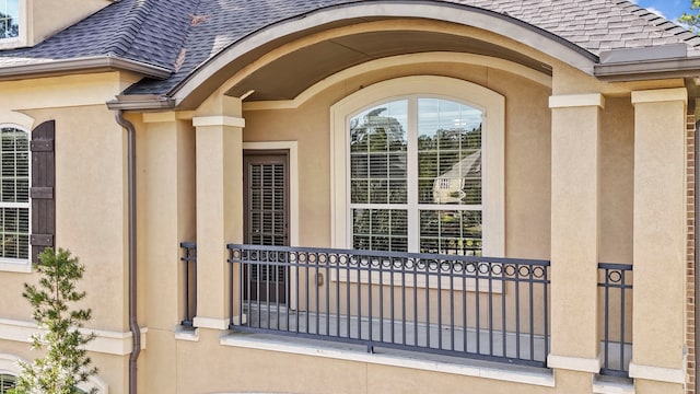 doorway to property featuring a shingled roof and stucco siding