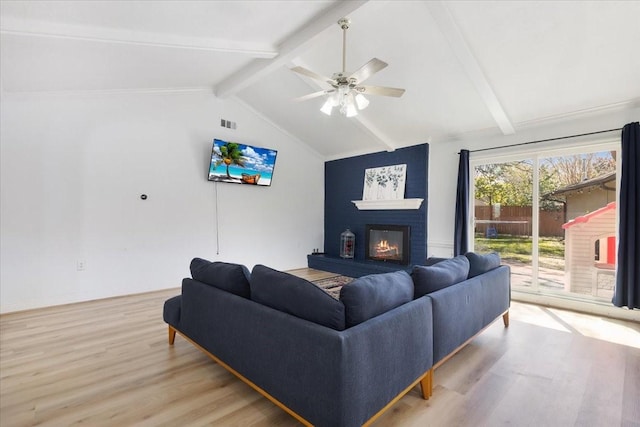 living room featuring vaulted ceiling with beams, ceiling fan, light wood-style flooring, a fireplace, and visible vents