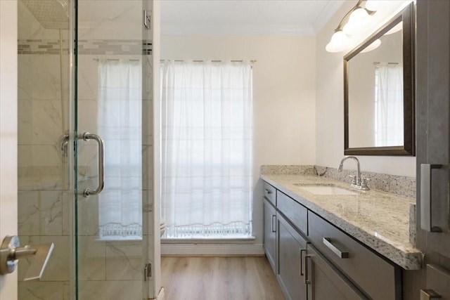 full bathroom with ornamental molding, a stall shower, wood finished floors, and vanity