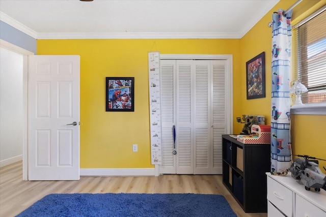 bedroom featuring light wood-type flooring, baseboards, ornamental molding, and a closet