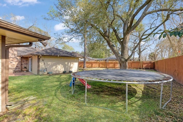 view of yard with a trampoline, an outdoor structure, and a fenced backyard