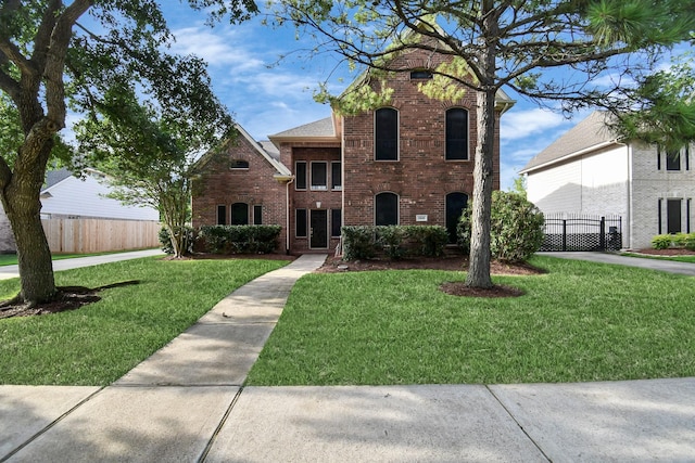 traditional home featuring brick siding, fence, and a front lawn