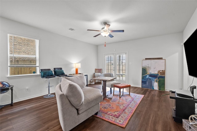 living room with a ceiling fan, visible vents, dark wood finished floors, and baseboards