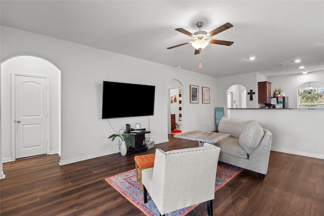 living area featuring arched walkways, dark wood-style flooring, recessed lighting, ceiling fan, and baseboards