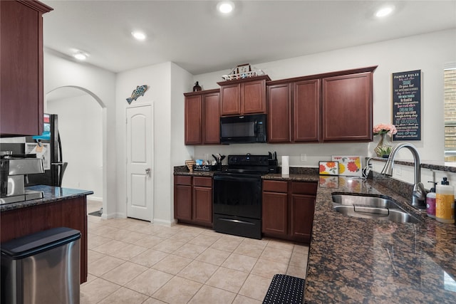 kitchen with arched walkways, dark stone counters, a sink, and black appliances