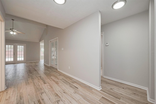 spare room featuring lofted ceiling, french doors, light wood-type flooring, and baseboards