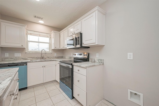 kitchen featuring light tile patterned floors, visible vents, appliances with stainless steel finishes, white cabinetry, and a sink