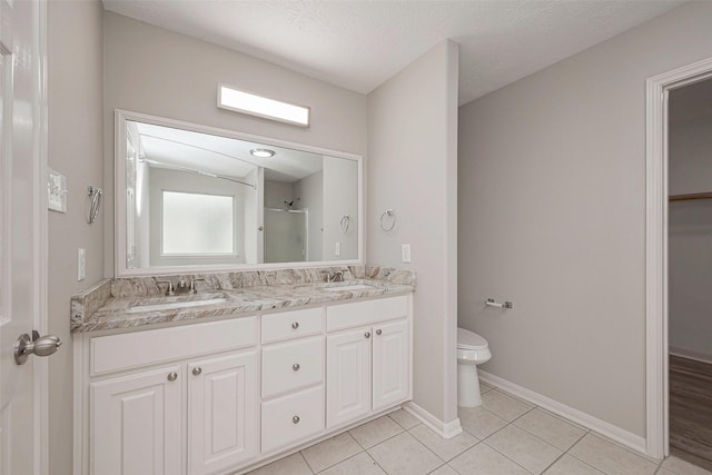 full bathroom featuring double vanity, a stall shower, a sink, and toilet