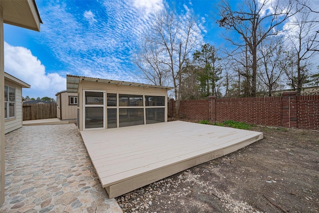 wooden terrace featuring a sunroom, a fenced backyard, and a patio