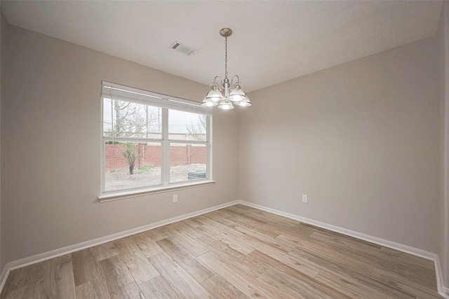 unfurnished room featuring visible vents, a notable chandelier, light wood-style flooring, and baseboards