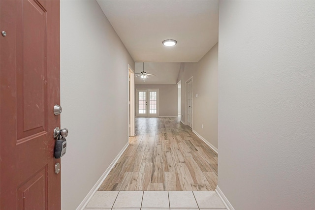 corridor featuring light tile patterned floors, french doors, and baseboards