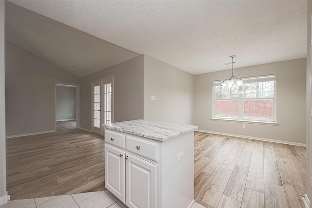 kitchen featuring pendant lighting, a kitchen island, white cabinets, and light wood-style floors