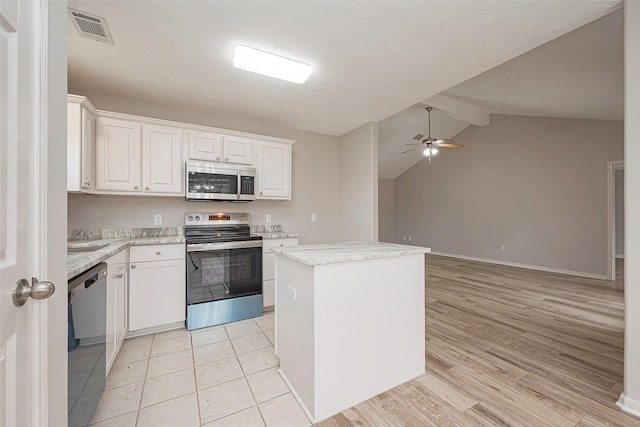 kitchen featuring visible vents, appliances with stainless steel finishes, a ceiling fan, white cabinets, and a kitchen island