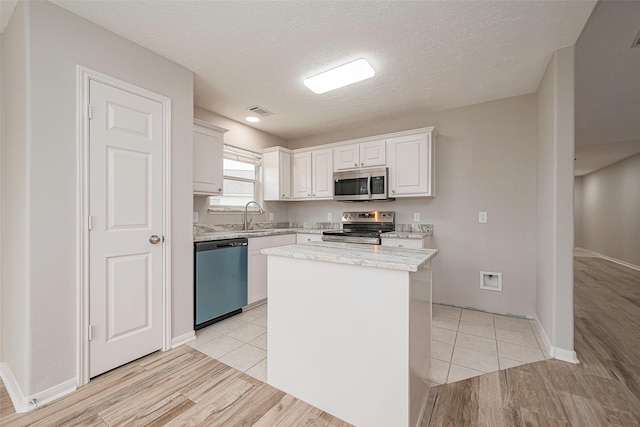 kitchen featuring visible vents, white cabinets, light wood-style flooring, appliances with stainless steel finishes, and a sink