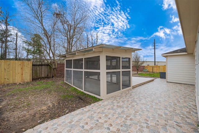 view of outdoor structure with a sunroom and a fenced backyard