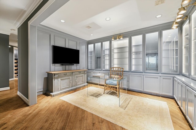 interior space with light wood-style flooring, ornamental molding, a decorative wall, and recessed lighting