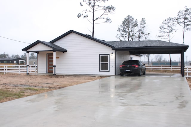 view of front of house with a carport, concrete driveway, and fence