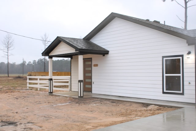 exterior space with a shingled roof and fence