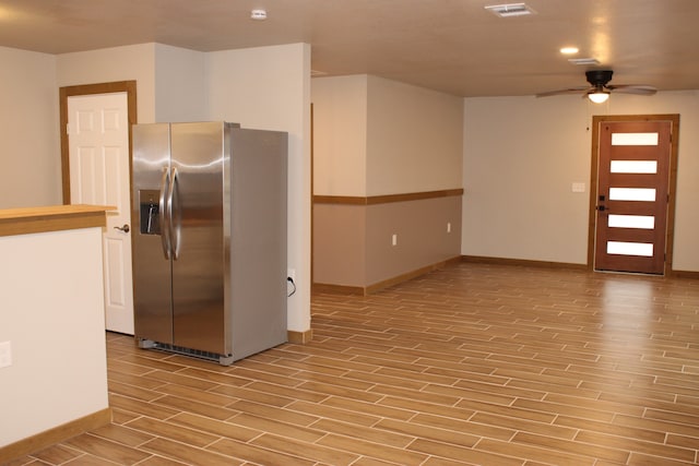 kitchen with wood finish floors, visible vents, baseboards, a ceiling fan, and stainless steel refrigerator with ice dispenser