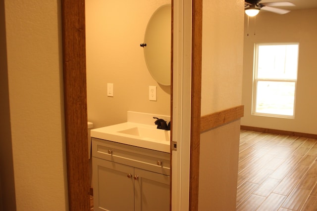 bathroom featuring a ceiling fan, vanity, baseboards, and wood finished floors