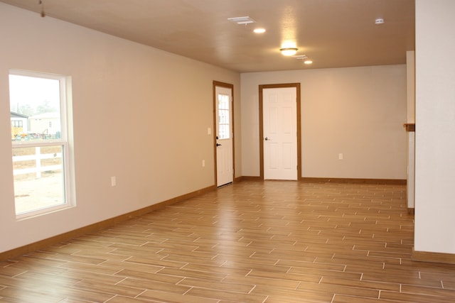 empty room featuring wood tiled floor, a healthy amount of sunlight, and baseboards