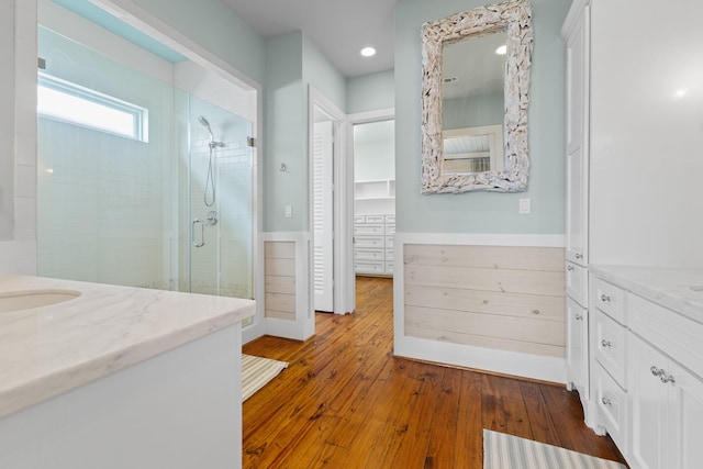 bathroom with recessed lighting, wood finished floors, vanity, and a shower stall