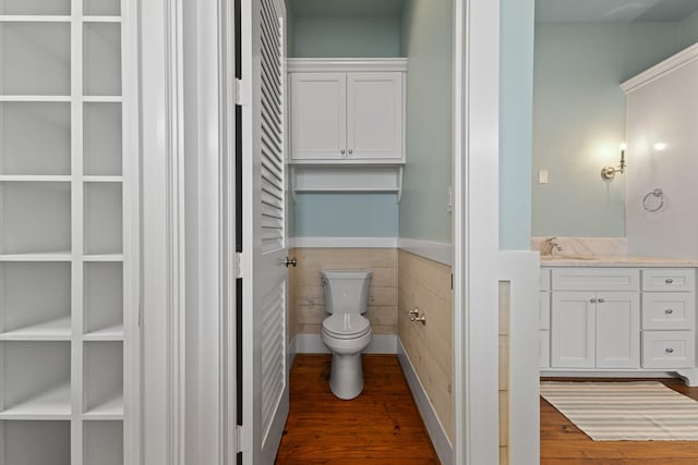 bathroom featuring a wainscoted wall, tile walls, a closet, toilet, and wood finished floors