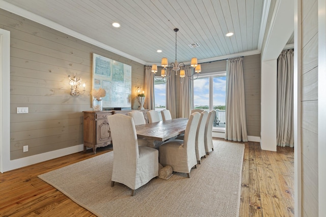 dining space with wood walls, wooden ceiling, light wood-style flooring, and a notable chandelier