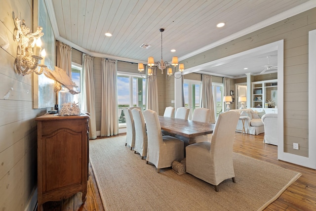 dining area featuring wood walls, visible vents, wood ceiling, light wood finished floors, and an inviting chandelier