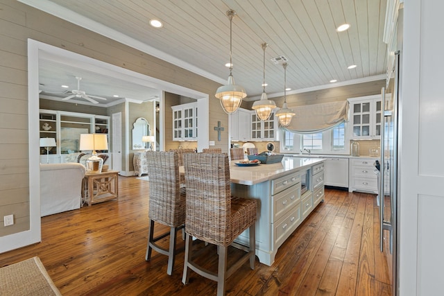 kitchen featuring glass insert cabinets, white cabinets, a breakfast bar area, and pendant lighting