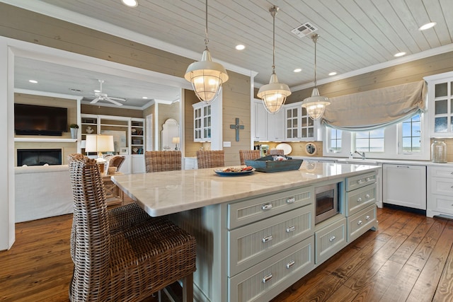 kitchen featuring hanging light fixtures, glass insert cabinets, white cabinets, a kitchen island, and a kitchen breakfast bar