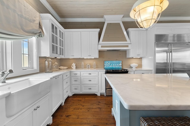 kitchen with stainless steel appliances, glass insert cabinets, ornamental molding, a sink, and premium range hood